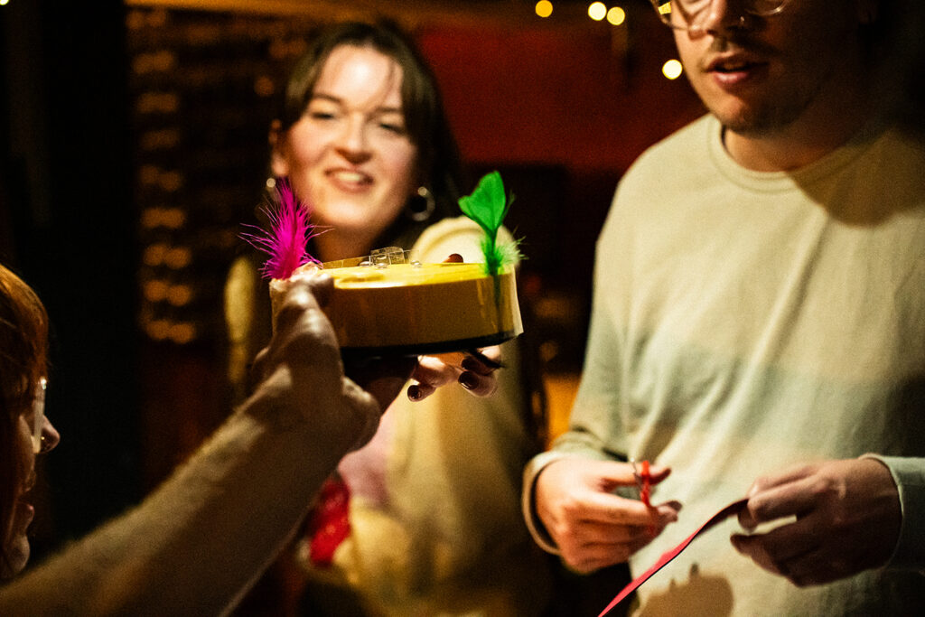 Participants holding a decorated robot vacuum with colorful accessories in a lively atmosphere.